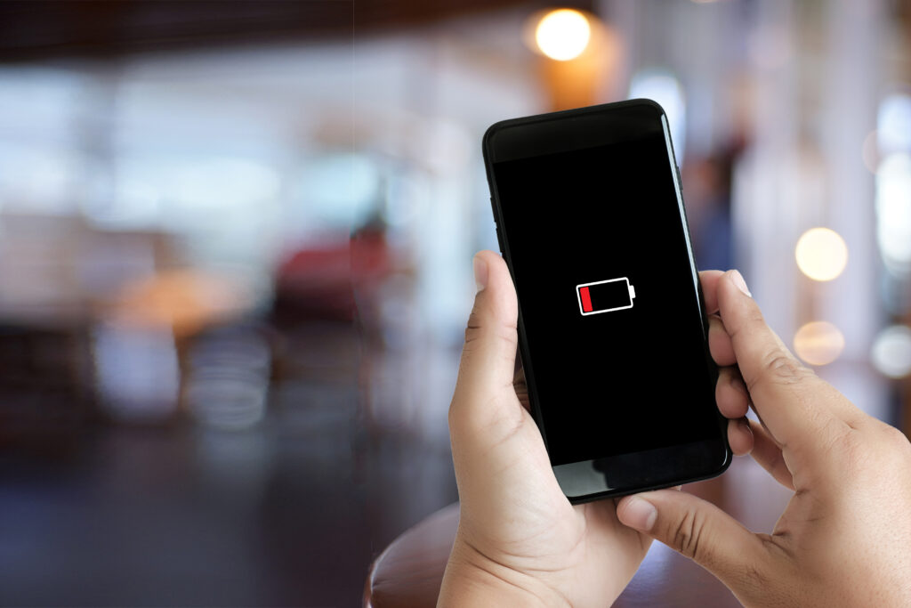 A person holding a phone displaying a low battery warning.