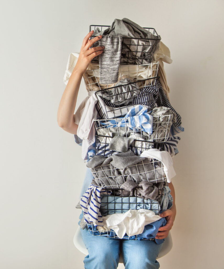 A woman carries a pile of folded laundry that's so tall it hides her face.