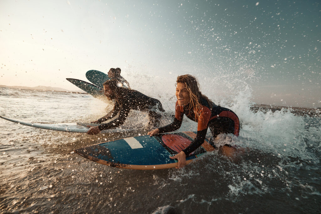 Exhilarated people laughing and riding their surfboards back to the beach.