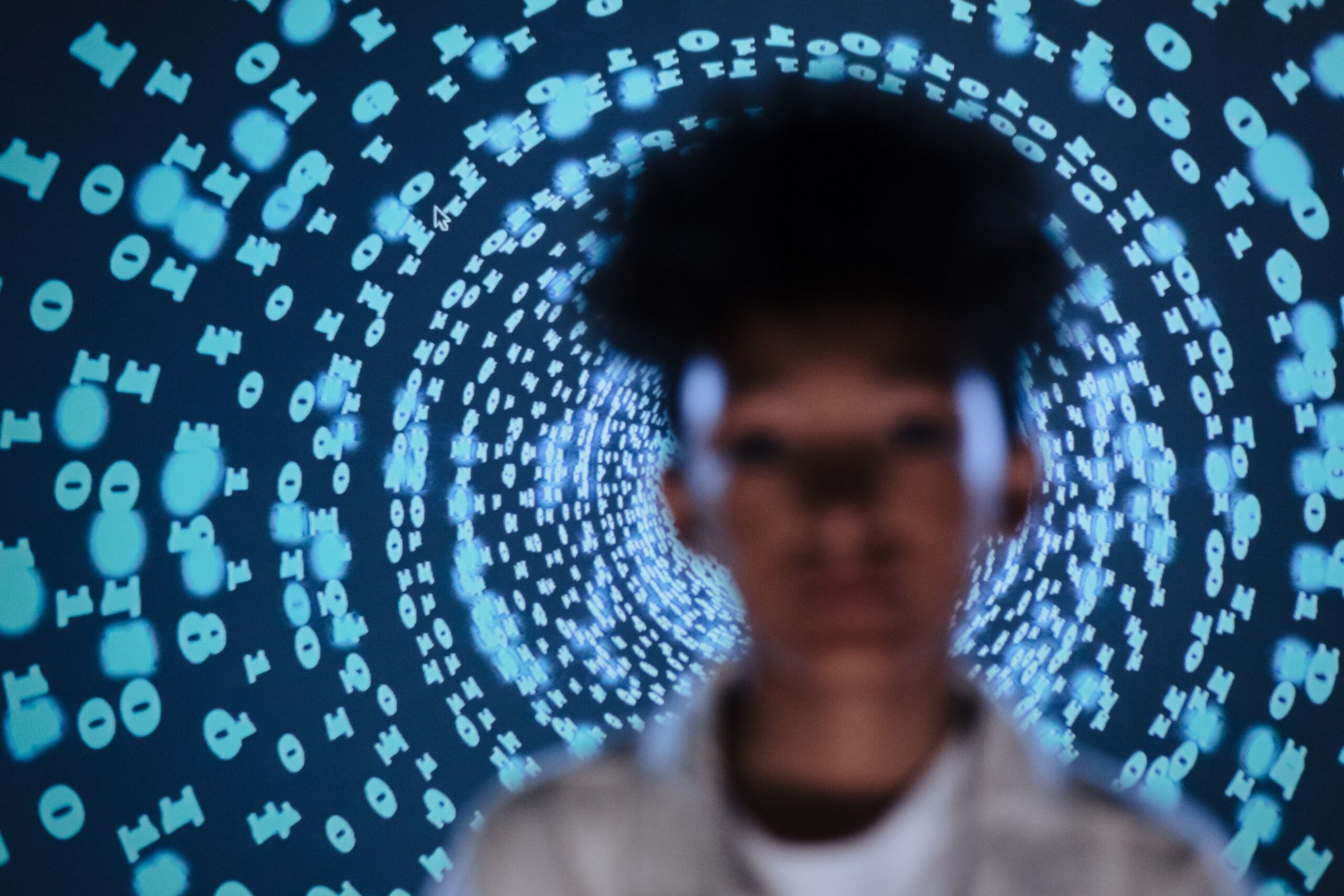 A person stands in front of an illuminated network of words and symbols
